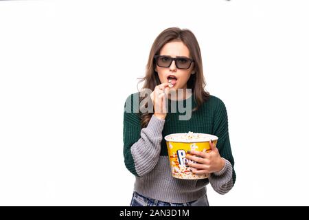 Porträt von einem aufgeregten Mädchen in der 3D-Brille holding Eimer Popcorn und entfernten Blick auf gelben Hintergrund isoliert Stockfoto