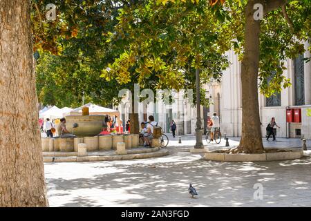 Lokale Italiener und Familien entspannen von Springbrunnen und unter Bäumen auf der Piazza della Vittoria in Brindisi, Italien. Stockfoto