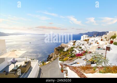 Eine Terrasse mit Blick auf die weiß getünchte Stadt Oia, Griechenland und blaue Ägäische Meer auf der Insel Santorini, Griechenland. Stockfoto