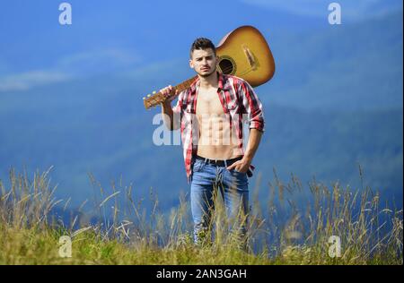 Mann mit Gitarre auf dem Gipfel des Berges. Beste weg von Stadt zu entkommen. Guy Wanderer Natur pur genießen. Ausflüge in die Natur. Schönheit der Natur. Frische Luft der Berge. Ferienhäuser Reiseziele. Allein gehen. Stockfoto