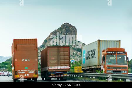 Die drei Fahrzeuge mit Containern, die parallel in der nationalen Autobahn in Indien felsigen Hügel im Hintergrund und anderen Fahrzeugen, die in der Entfernung Stockfoto