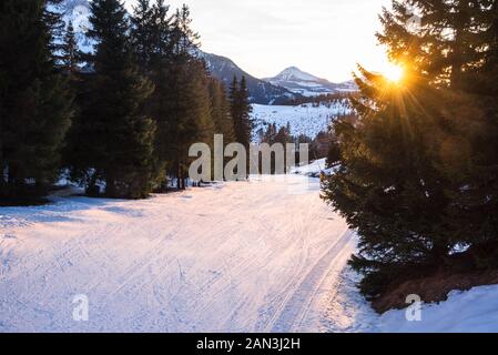 Sonnenuntergang über einem verlassenen Skipisten in den Alpen Stockfoto