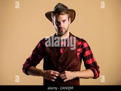 Cowboy Hut tragen. Westliche leben. Mann unrasiert Cowboy beigen Hintergrund. Unrasierten Kerl in Cowboyhut. Schöne bärtige Macho. American Cowboy. Schönheit Standard. Beispiel wahrer Männlichkeit. Stockfoto