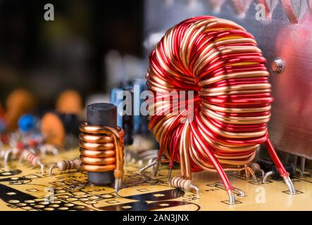 Spule Kupferdraht Wicklung. Elektronische Komponenten in der Platine gelötet. Toroidal und zylindrisch Induktionsspulen. Reflexion auf Aluminium Kühlkörper. Stockfoto