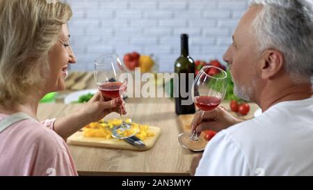 Liebe im Alter von Paar hält Gläser mit Rotwein sitzen Home Küche, Kochen Stockfoto