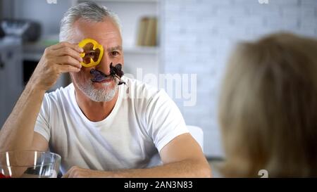 Lustige älterer Mann etwa täuschen mit frischem Gemüse, Pfeffer Slice Stockfoto