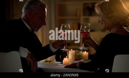 Ältere männliche und weibliche Toasten mit Weingläsern, im Alter von Paar flirten auf Datum Stockfoto
