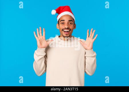 Mann Fang präsentiert in santas Hut. Fröhliche afrikanisch-amerikanischen jungen Kerl schnappen Sie sich etwas und hob die Hände und wartet auf Fang, freudig lächelnd Stockfoto