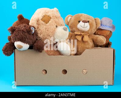 Braun Karton mit verschiedenen Teddybären, blauer Hintergrund, Konzept der Hilfe und Freiwilligenarbeit Stockfoto