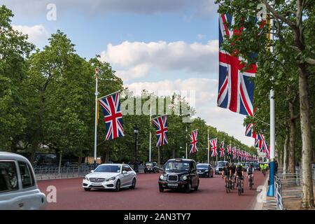 Die Flaggen von Union Jack fliegen im Frühjahr von Straßenpflaster in Der Mall, City of Westminster, London, Großbritannien mit grünen Bäumen und blauem Himmel Stockfoto