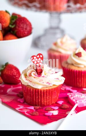 Eine Nahaufnahme der Erdbeere Cupcakes mit Frischkäse Zuckerguss und streuseln für den Valentinstag Stockfoto
