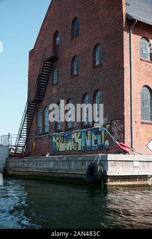 Graffiti auf der Seite eines Gebäudes durch den Kanal in Kopenhagen, Dänemark. Stockfoto