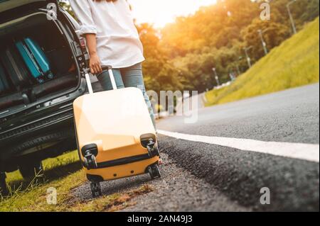 Rückansicht des gelben Koffer schleppen Gepäck Koffer allein Road Trip zum Laden in SUV-Auto. Menschen Lebensstile und Ferienhäuser Konzept. Natur und Su Stockfoto