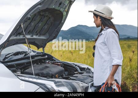 Asiatische Frau mit Hilfsbatterie kabel Kupferdraht für Instandsetzung Aufteilung Auto von connect mit roten und schwarzen Linie zu elektrischen Terminal, indem er Stockfoto