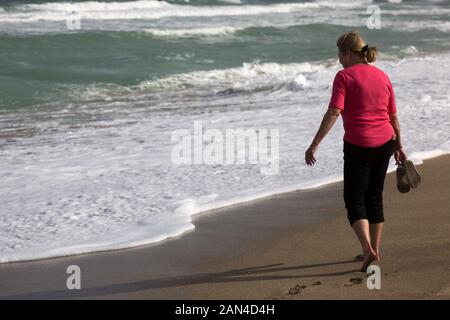 Eine barfuß Frau nähert sich das schaumige Surf auf dieser Hutchinson Island Beach in Stuart, Florida, USA. Stockfoto