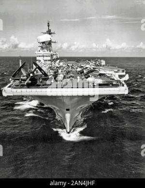 Bugansicht des britischen Flugzeugträgers der Royal Navy, HMS Victorious (R38), der zwischen dem 15. Und 20. Juli 1959 in der Nähe von Norfolk, Virginia (USA) operiert. An Deck befinden sich mehrere Flugzeuge der Luftgruppe Victorious: Eine Douglas Skyraider AEW.1 von 849 Naval Air Squadron, fünf de Havilland Sea Venom Kämpfer von 893 NAS, zwei Supermarine Scimtar Kämpfer von 803 NAS und eine Westland Dragnonfly HR.5 von Schiffen Flug 1 (Suche und Rettung). Ebenfalls an Deck sind serverale Flugzeuge der US-Marine (Steuerbordbogen): Eine McDonnell F3H-2 Demon der Fighter Squadron 31 (VF-31) "Tomcatters" und ein kaum sichtbarer Vought F8U-1E Crusader (BuNo 145544) Stockfoto