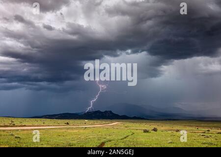 Ein Blitzschlag trifft auf einen Bergrücken, während sich ein Sommergewitter von der Front in der Nähe von Walsenburg, Colorado, bewegt Stockfoto