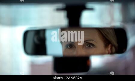 Pensionierte business Frau an ihr Spiegelbild im Rückspiegel suchen, Treiber Stockfoto