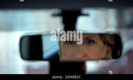 Alte Dame auf ihr Spiegelbild im Rückspiegel, Auto kaufen, testen Stockfoto