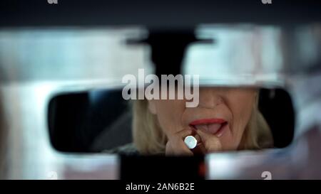 Elegante älteren Dame Vorbereitung für Datum, Anwendung Lippenstift, im Auto Spiegel Stockfoto