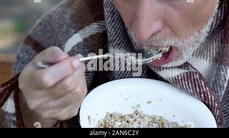 Alter Großvater essen Porridge, liebe Essen für arme Rentner, Armut Stockfoto