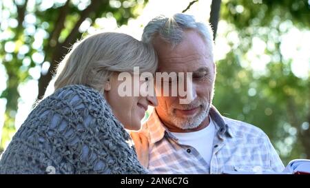 Reifes Paar beobachten Familie Album sitzt auf der Bank im gemütlichen Garten, Nostalgie Stockfoto