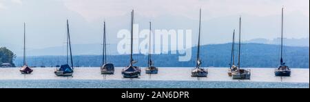 Panorama-Blick auf Segelboote, die am Ammersee ankern. Die Kirche im Hintergrund ist Marienmünster Dießen. Segeln ist eine beliebte Aktivität in der Nähe von Seen. Stockfoto