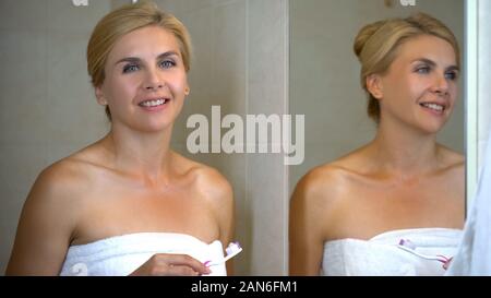 Pretty Woman holding Zahnbürste mit Zahnpasta in die Kamera schauen und lächeln Stockfoto