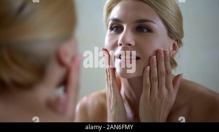 Glückliche Frau berühren Gesicht, gute Wirkung von Anti Aging Lotion, tägliche Hautpflege Stockfoto