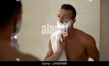 Mann Anwendung Rasierschaum zu Gesicht und Bart, bereit, das Aussehen, den Stil zu ändern. Stockfoto