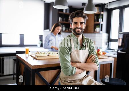 Glückliche junge Freunde Paar Köche in der Küche kochen. Stockfoto