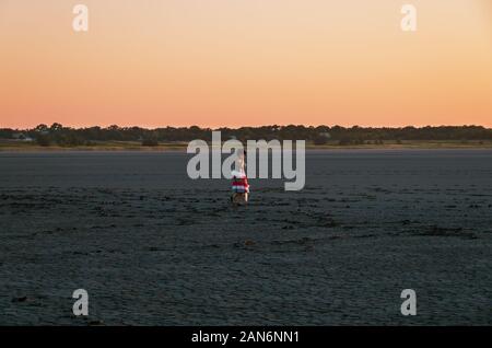 Erwachsene Frau zu Fuß entlang der Unterseite des ausgetrockneten Salt Pond am Abend bei Sonnenuntergang Stockfoto