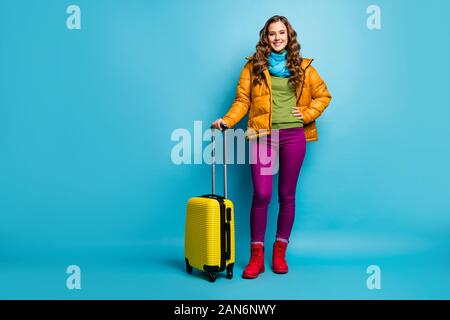 Volle Länge Foto ziemlich wellig Dame Reisende halten rollenden Koffer warten Flughafen Flug Registrierung tragen gelbe Jacke blau Schal Hose Stockfoto