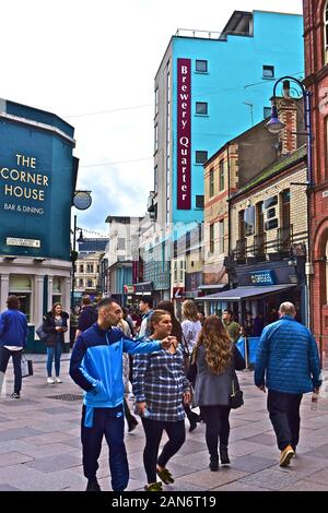 Blick auf den Beginn der Caroline Street im Stadtzentrum von Cardiff. Das Haus beherbergt das Brewery Quarter, eine Sammlung von Geschäften, Bars und Restaurants. Menschen, die vergehen. Stockfoto