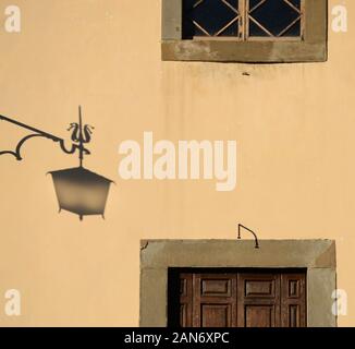 Stadtansicht einer rosa Wand eines antiken Gebäudes mit einem Straßenlampenschirm, einem Fenster und einer Holztür Stockfoto