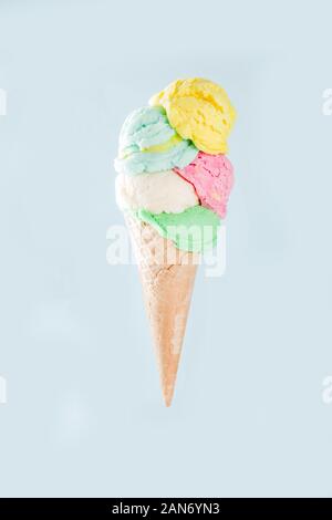 Stapel von Pastell bunte Eis Schaufeln im Waffle Kegel, auf hellblauem Hintergrund isoliert. Frau Hand hält grosse Eis mit unterschiedlichen Geschmack Stockfoto