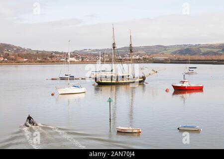 CONWY, Großbritannien - Februar 26., 2012. Ein Mann lenkt ein Beiboot auf dem Fluss Conwy in Richtung Boote in Conwy historische Stadt im Norden von Wales günstig Stockfoto