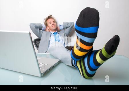 Sleepy Geschäftsmann entspannen mit seinen Socken auf dem Schreibtisch neben seinem Laptop Stockfoto