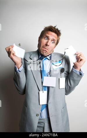 Verwirrt Büroangestellter indundated mit leeren Namensschilder, mit einem lustigen Ausdruck bei einem leeren Platz kopieren Stockfoto