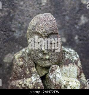 Alte buddhistische Stein Relikt mit beschädigten Kopf, mit Moos und Flechten bedeckt. Umiyama, Präfektur Fukui, Japan. Stockfoto