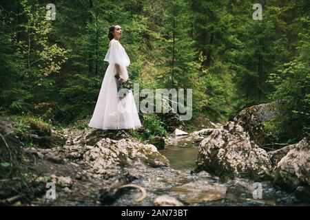 Schöne Braut im weißen Kleid posiert in der Natur Stockfoto