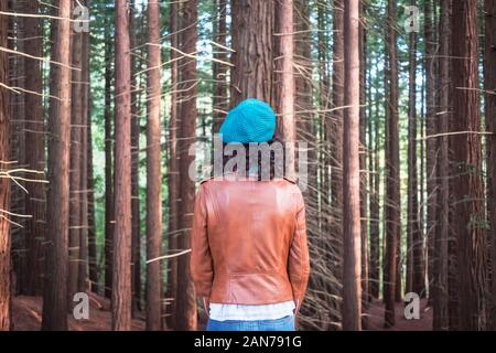 Frau trägt eine braune Lederjacke und grün Flach-runde hat sich auf dem Baum Wald suchen Stockfoto