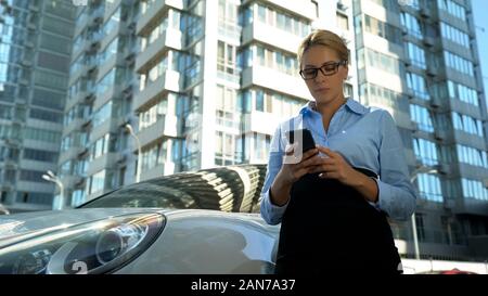 Junge Frau liest Nachricht auf dem Smartphone konzentriert, Personalabbau bei der Arbeit Stockfoto