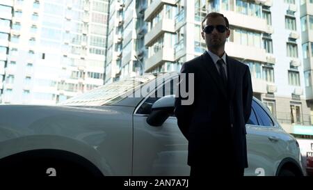 Männliche Bodyguard steht in der Nähe des Fahrzeugs, indem sie Sicherheit für vip Person Stockfoto