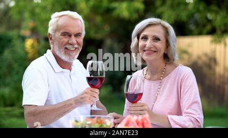 Schönes älteres Paar in die Kamera schaut, Weingläser, dating website Stockfoto
