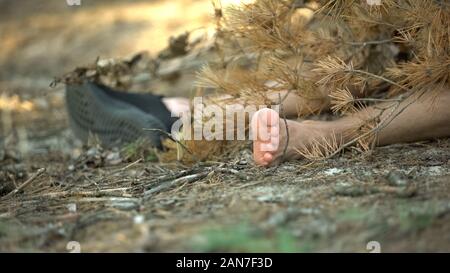 Leiche in einem Schuh mit Ast liegen auf Boden bedeckt, Mord im Wald Stockfoto