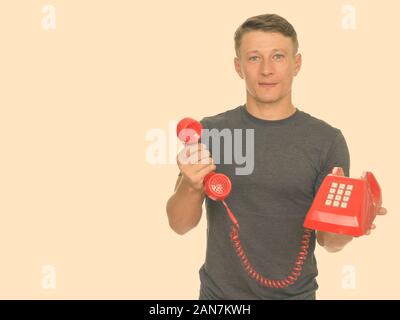 Studio shot der Jungen stattlichen kaukasischen Mann, der alten roten Telefon Stockfoto