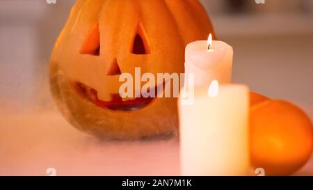 Lächelnd geschnitzten Halloween Kürbis mit unheimlichen Gesicht durch brennende Kerzen beleuchteten Stockfoto