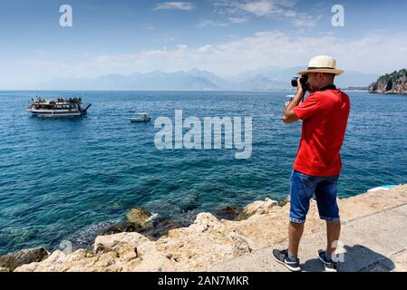 Antalya, Türkei - Juli 26, 2019, ein Mann in einem roten T-Shirt, Hut und Hose ist der Aufnahme in der alten Stadt Marina in einem schönen Sommer sonnigen Tag Stockfoto