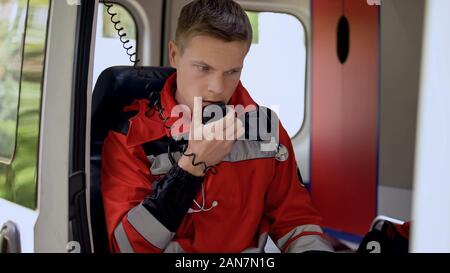 Männliche Sanitäter im Gespräch mit Radio, sitzen in Krankenwagen, bereit, auf Abruf zu fahren Stockfoto